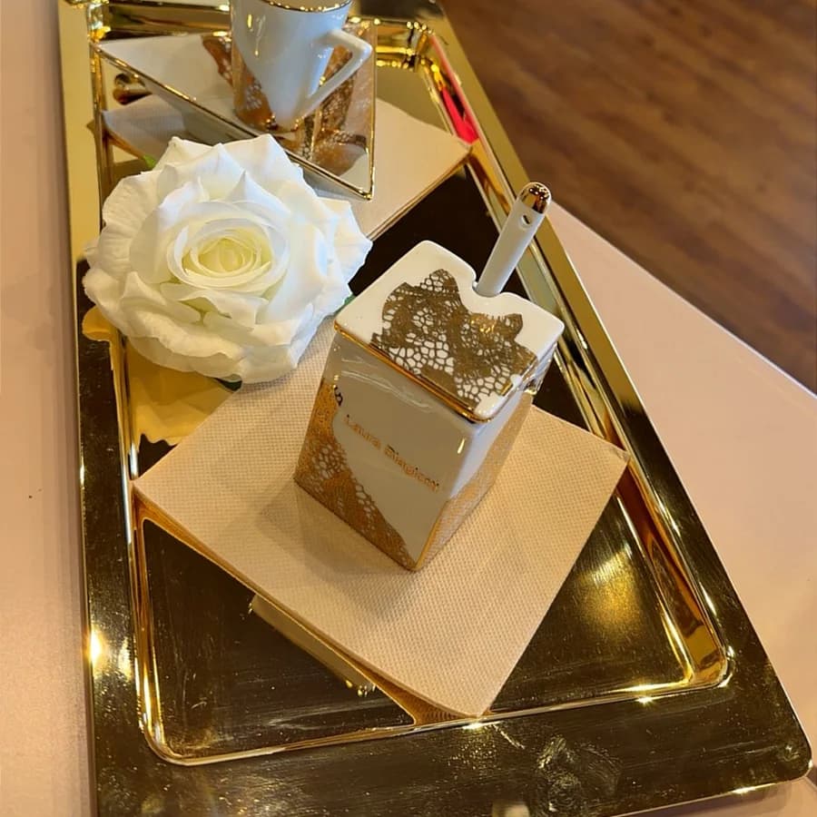 Plateau doré, bougie et rose blanche sur le comptoir de la boutique